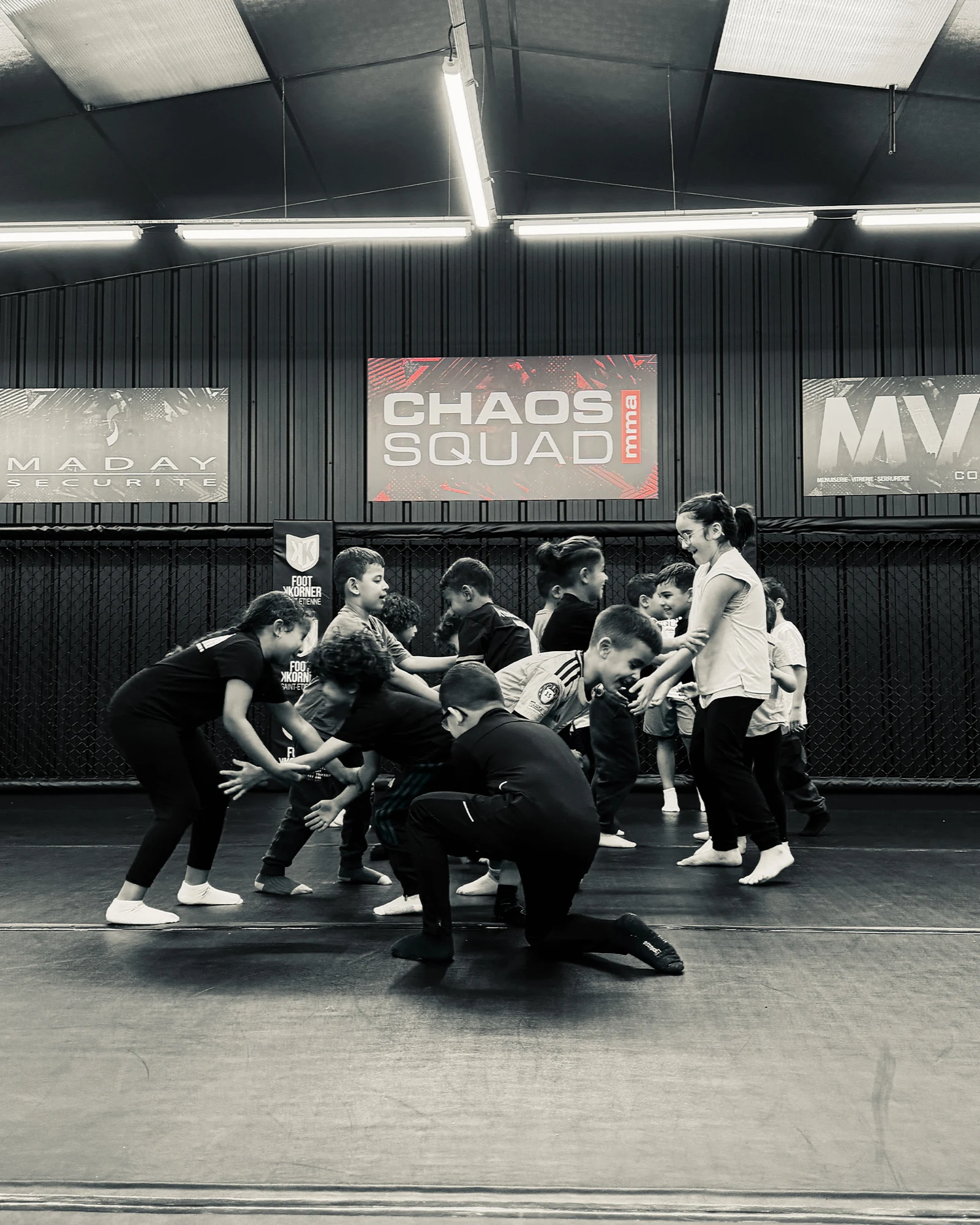 Les jeunes de CHAOS SQUAD s’entraînent ensemble sur le tapis, sous le logo du club